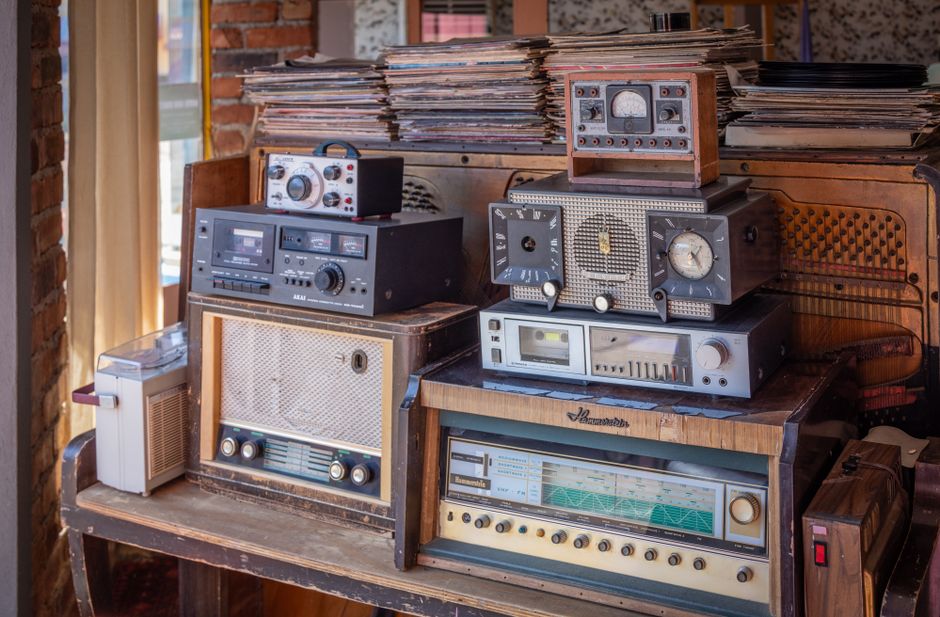 A charming interior featuring a collection of vintage radios and a stack of vinyl records on an antique wooden cabinet.
